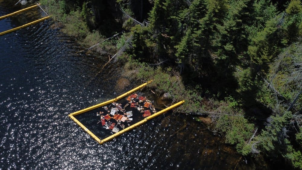 Rectangular plastic partition within a dark blue lake next to trees