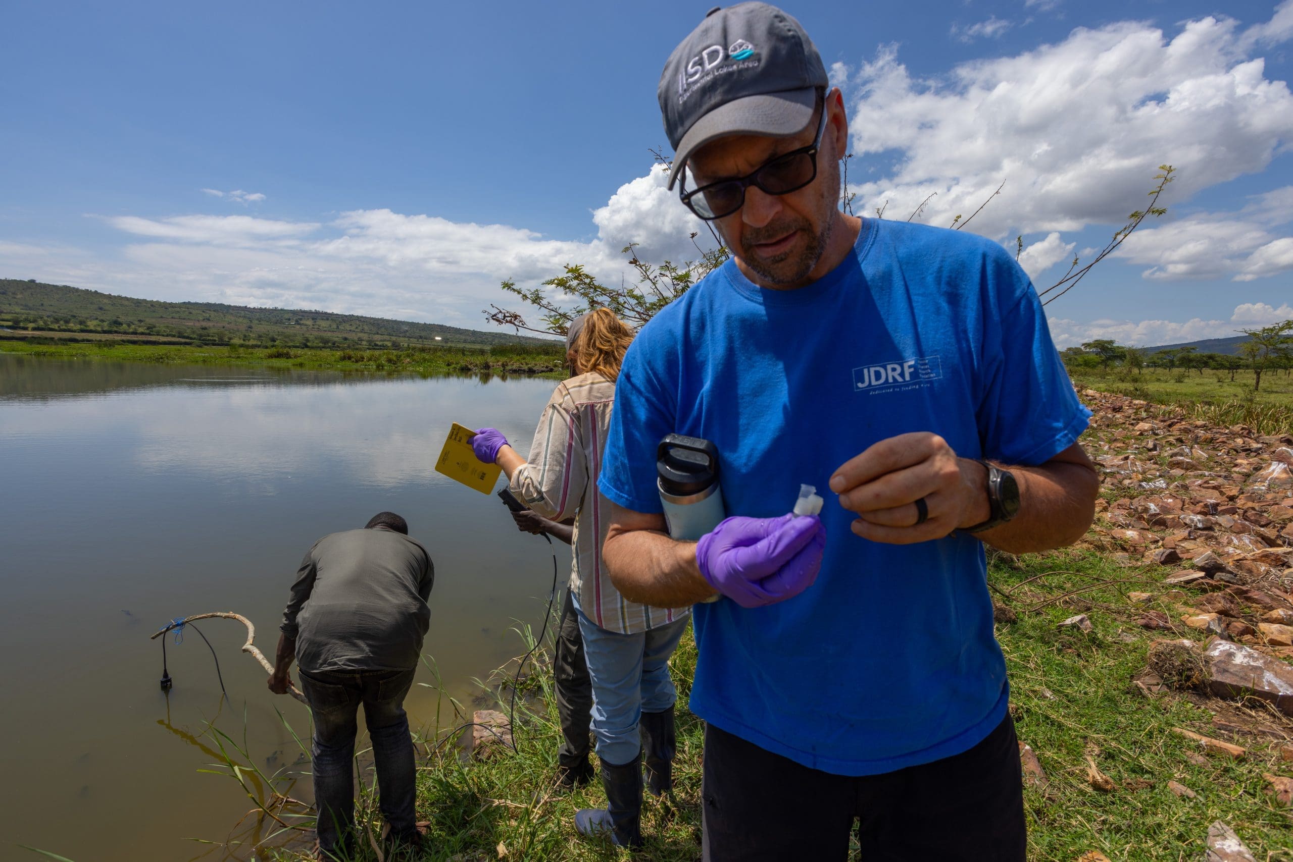 Vince Palace collects a very small volume of water from a pond while Simon Muhayimana places the YSI probe to collect in situ temperature, pH, salinity and oxygen information. This tiny tube of water will be used to assess what pesticides and herbicides might be contaminating this water.